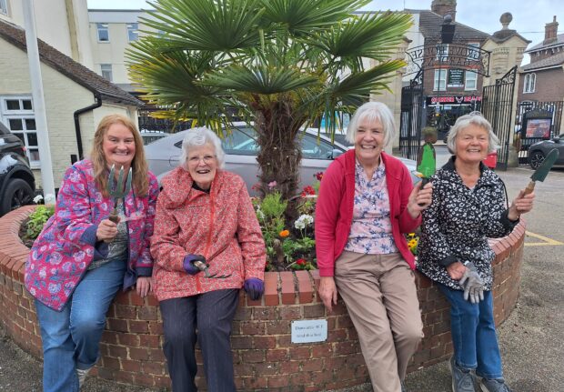 W.I ladies in front of flower bed in Grove House Gardens