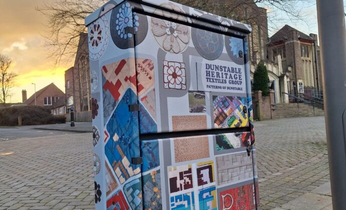 electrical box wrapped in a graphic with a church in the background with the sun just setting