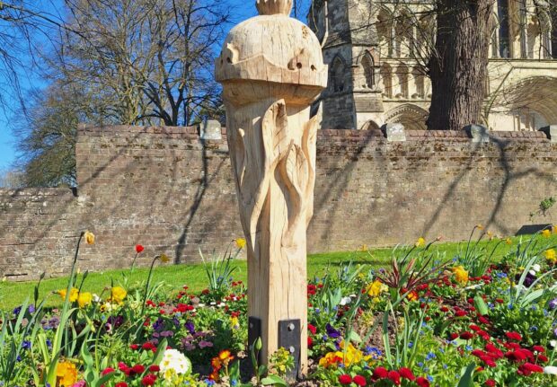 pomegranate wooden sculpture in a bed of flowers