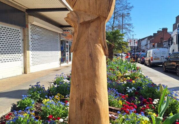 bonnet wooden sculpture in a bed of flower beds