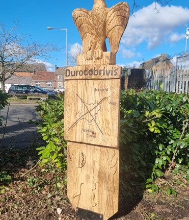 wooden sculpture with engraved road and eagle on top