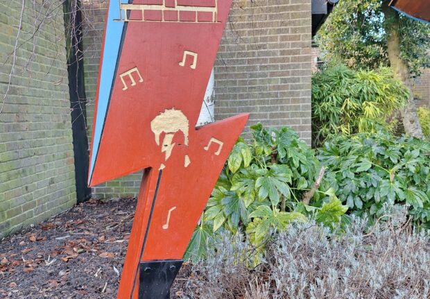 red lightening bolt sculpture with gold graphics