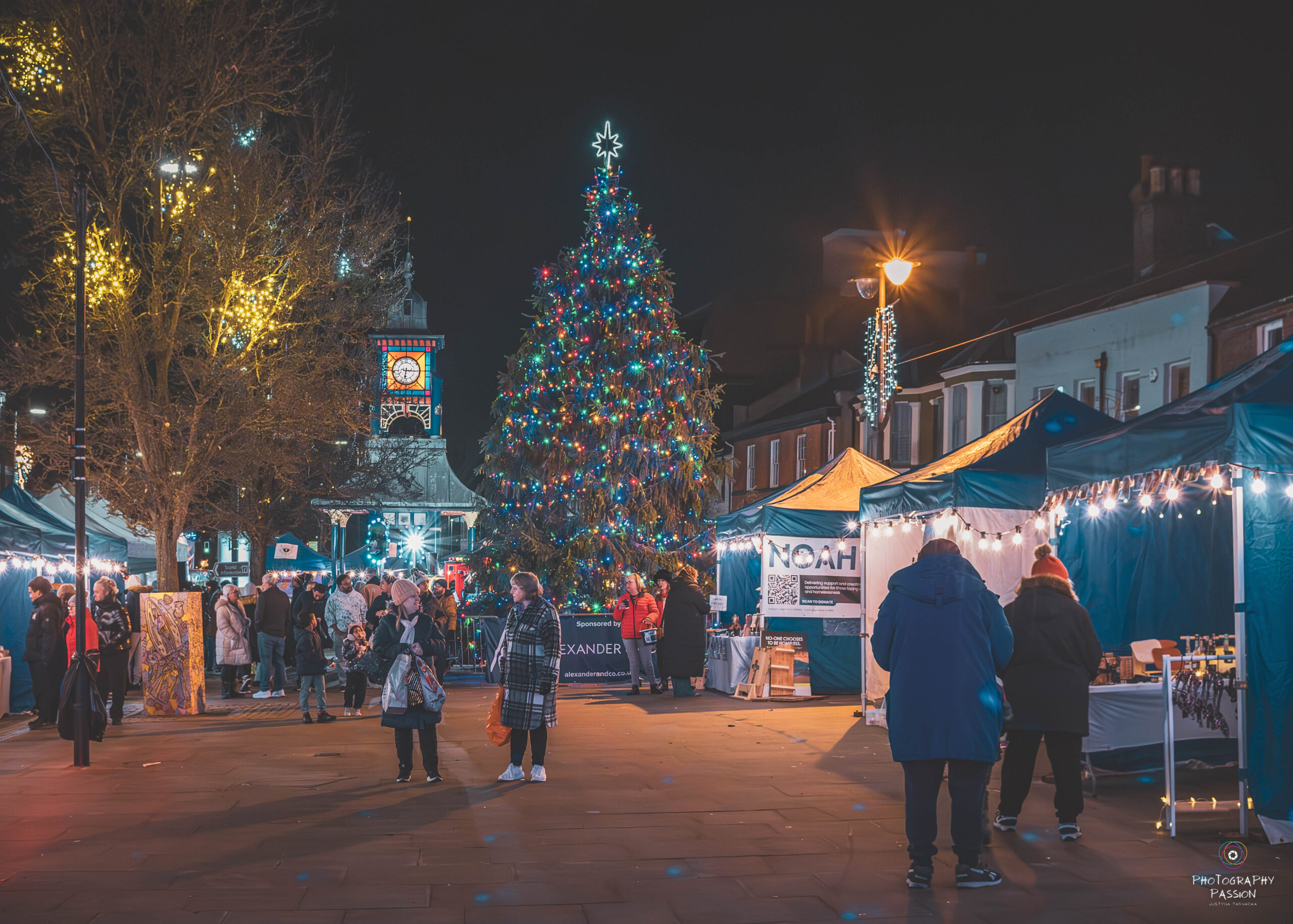 stalls and people in the square with a chritmas tree in the background