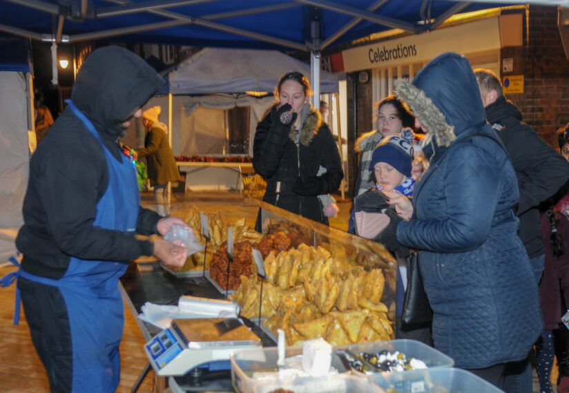 A market stall selling multiple different foods with customers buying