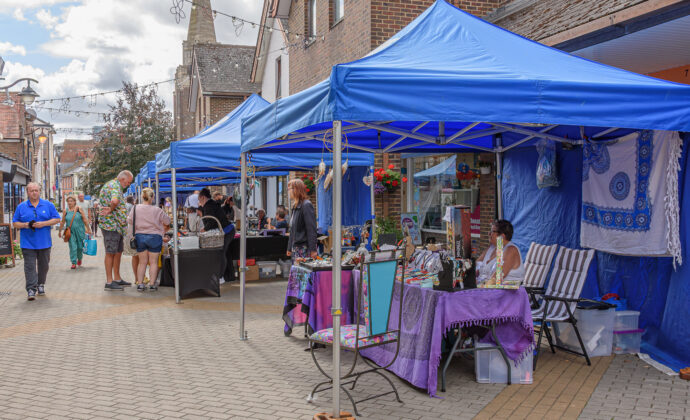 people walking with blue gazebo stalls with people selling products