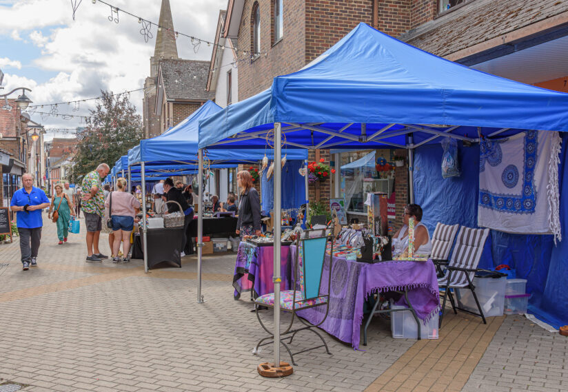 people walking with blue gazebo stalls with people selling products