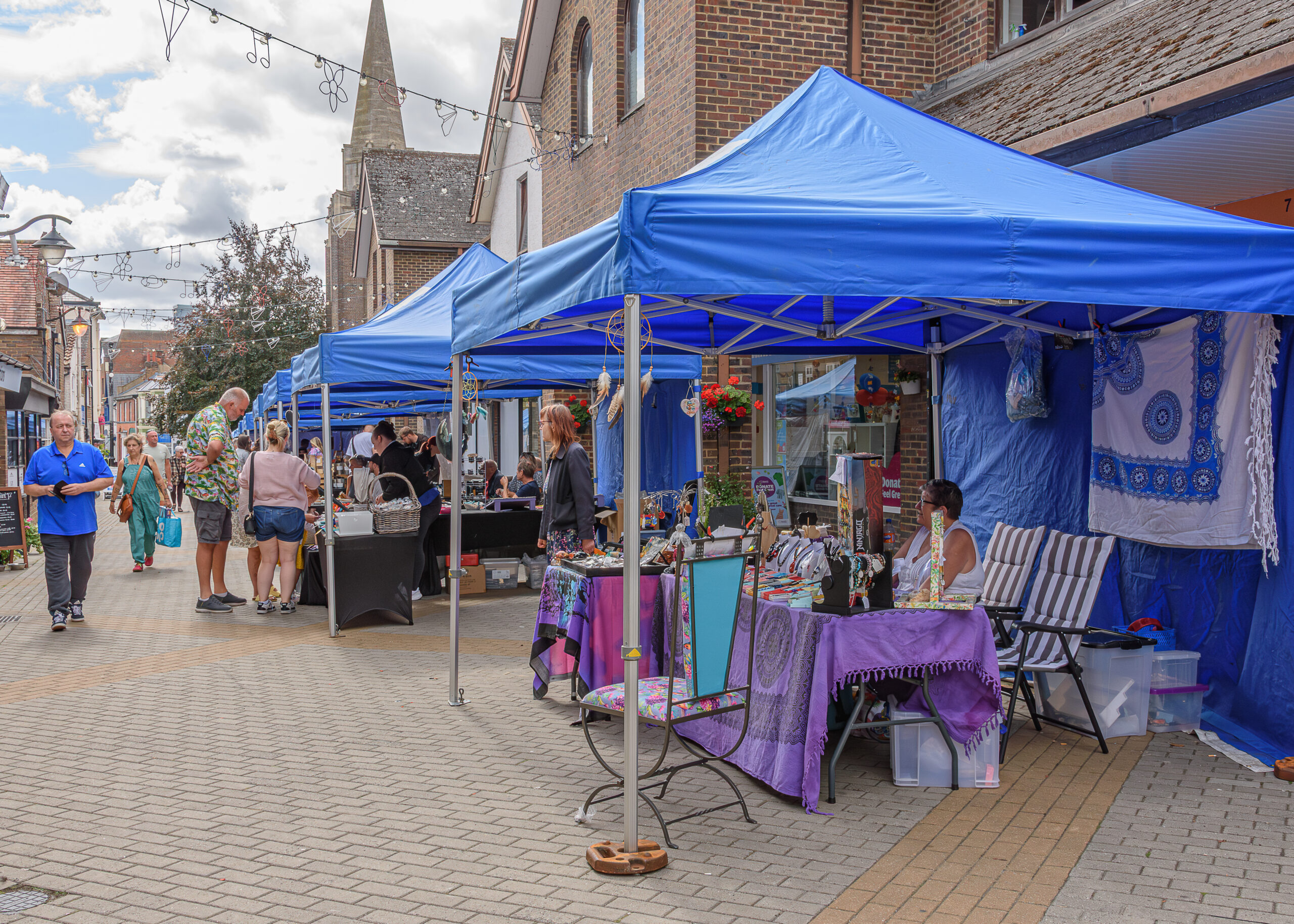 people walking with blue gazebo stalls with people selling products