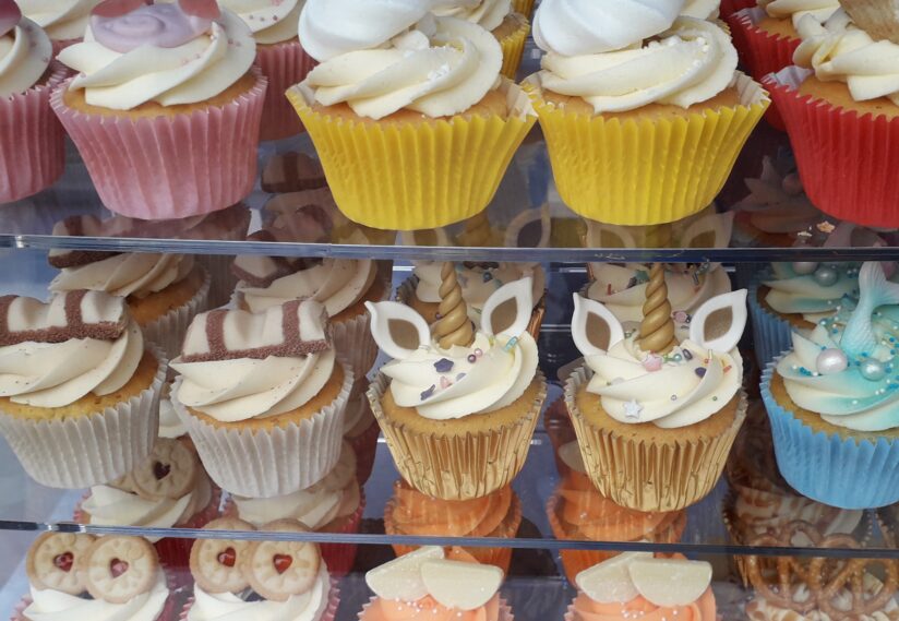 A bunch of little muffin cakes all with multiple decorations on top of them from the Cake House