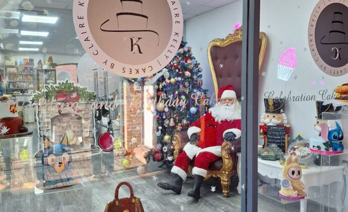 Christmas Window with Santa in a chair next to a large Christmas tree, Santa is eating cake and having a cup of tea
