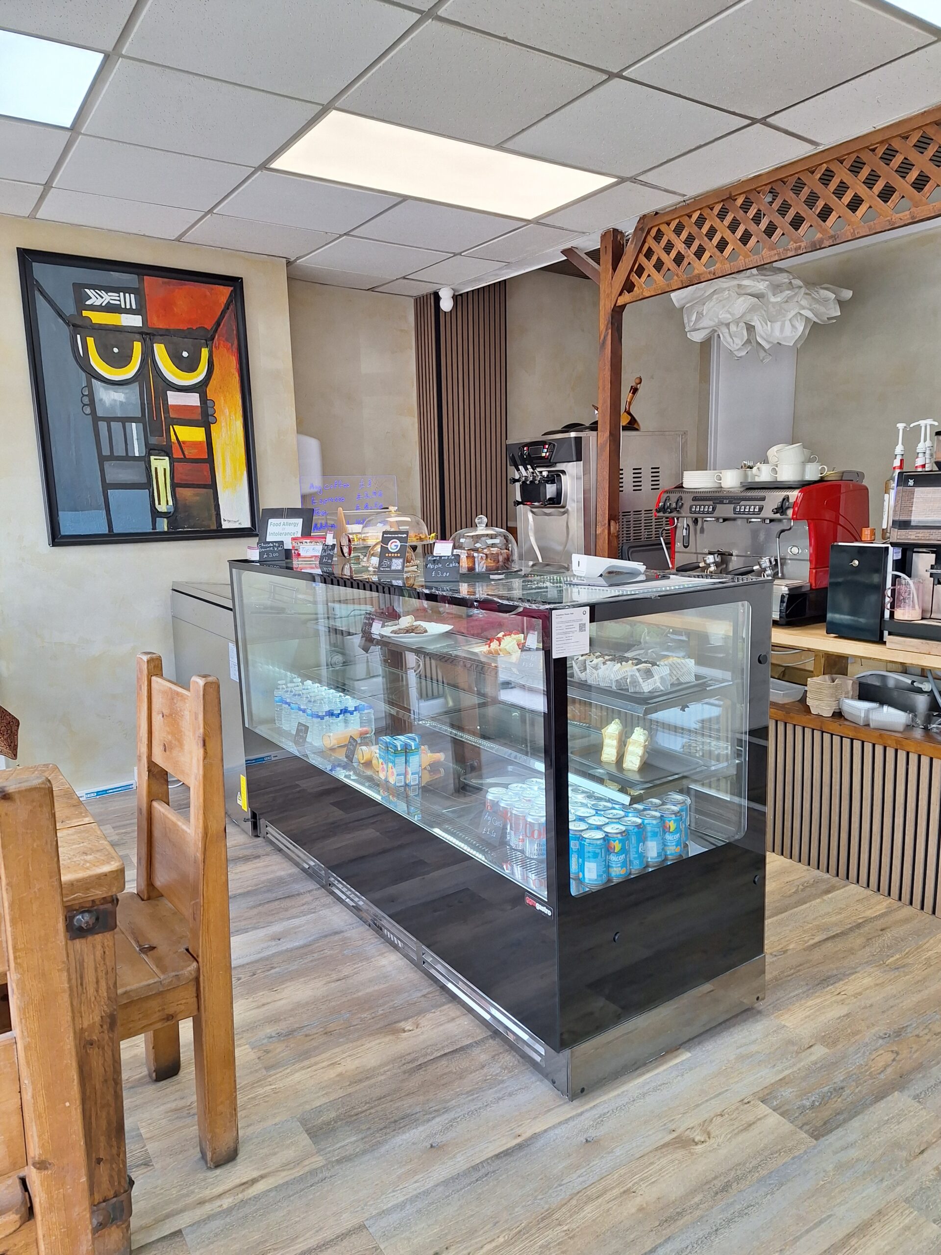 inside cafe showing counter and cakes with coffee machine behind the counter