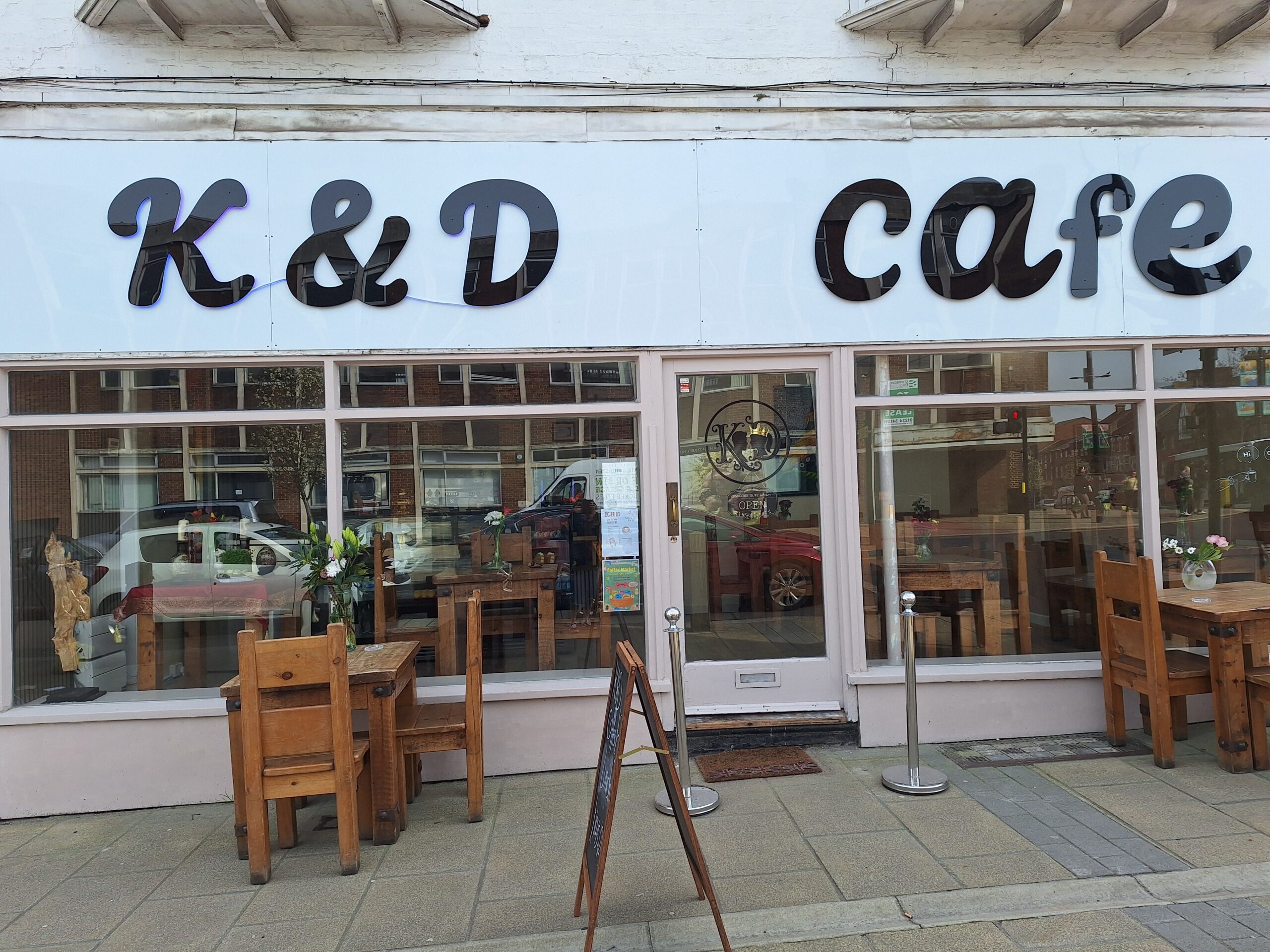 K & D cafe front with chairs outside on the street
