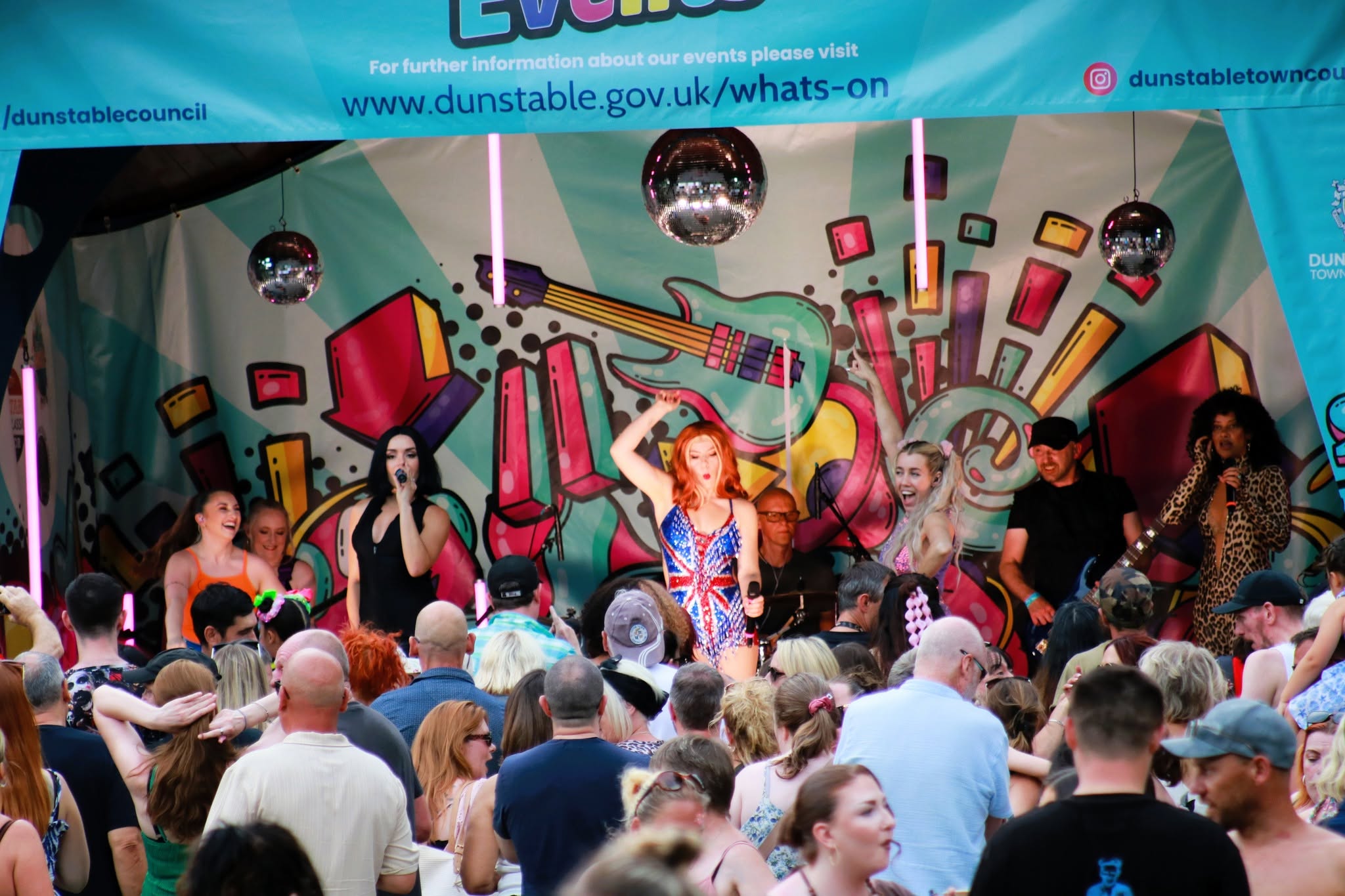 crowds of people with the tribute act the spice girls performing in the background