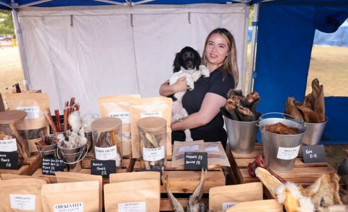 skye holding her dog with her stall of dog products