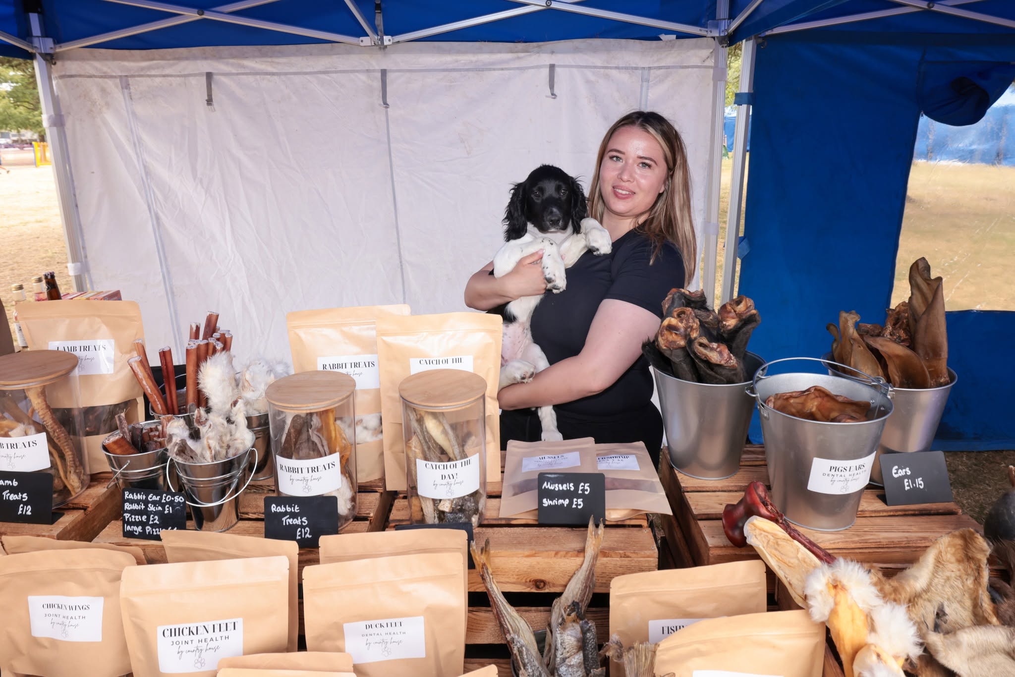 skye holding her dog with her stall of dog products